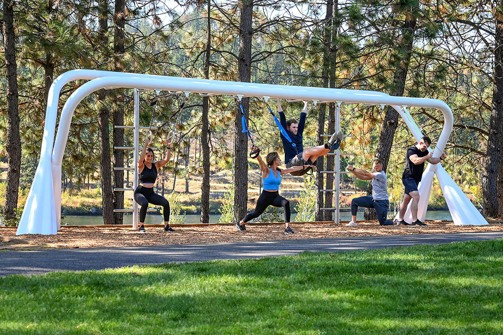 Five people working out on outdoor gym equipment with gym accessories.