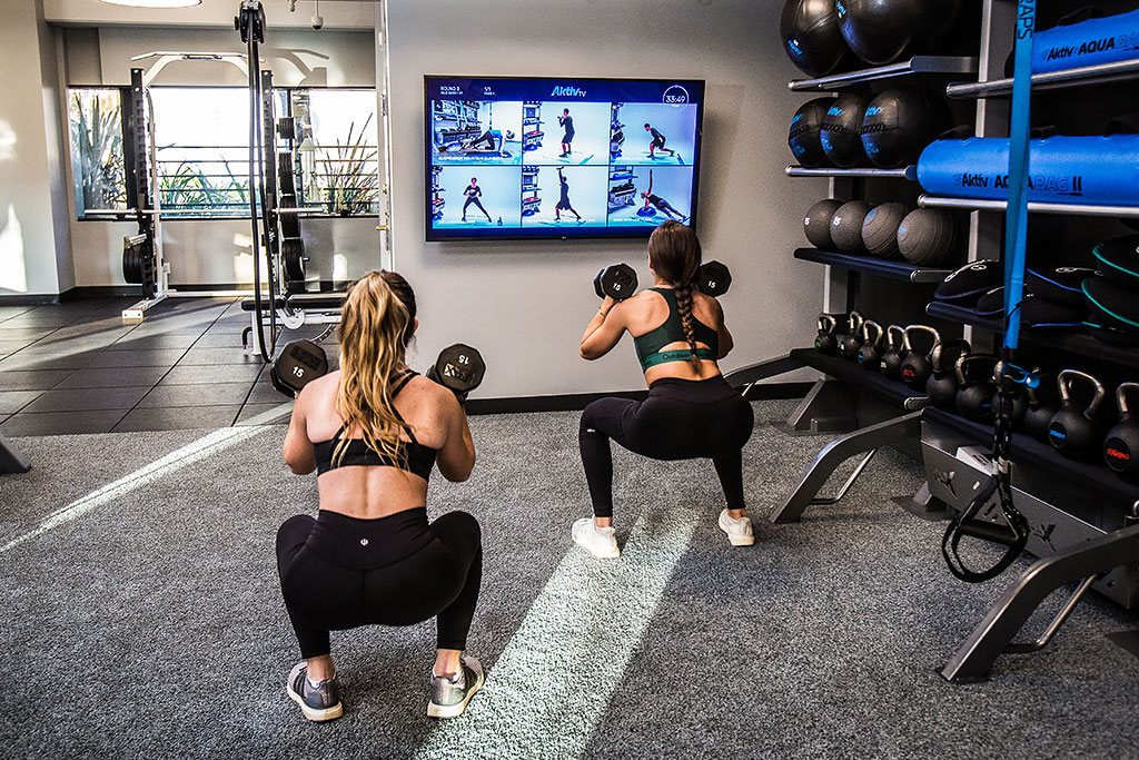 Two sets of Double Xponential+ Training Bays with digital exercise guidance on the wall and gym flooring.