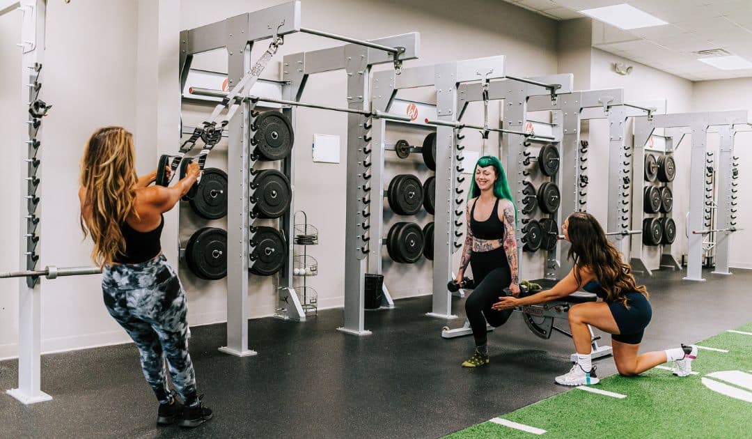 Three people working out in a boutique studio gym designed for strength training.