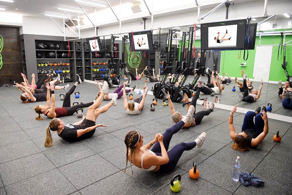 Xponential+ Functional Fitness on gym TV in amenity room with two Gym Rax storage bays and 3 mats.